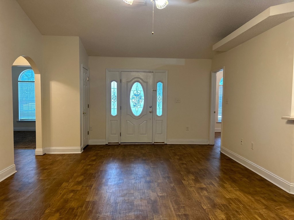 A room with wooden floors and a large arched window.
