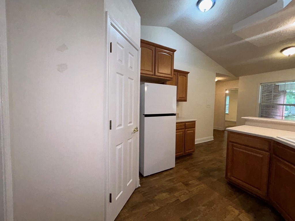 A kitchen with white appliances and wooden cabinets.