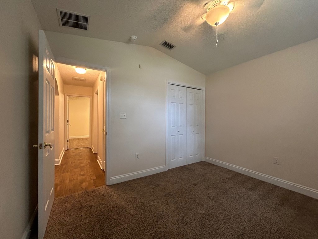 A room with a carpeted floor and a door on the right side.