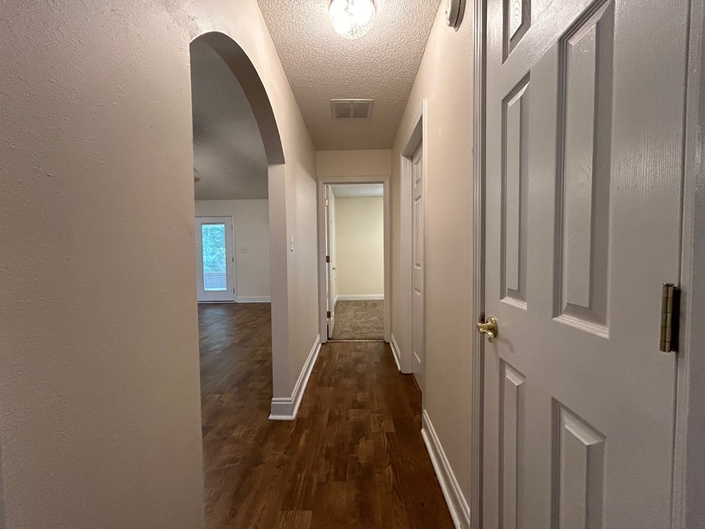 A hallway with a white door and a window in the distance.