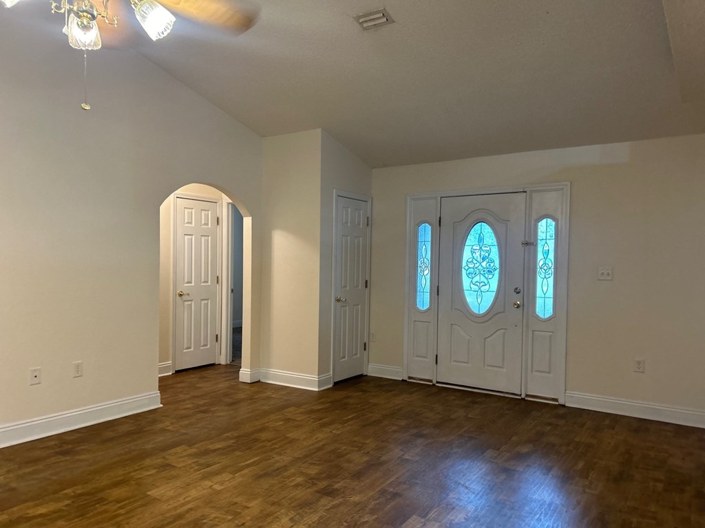A room with a wooden floor and three doors.