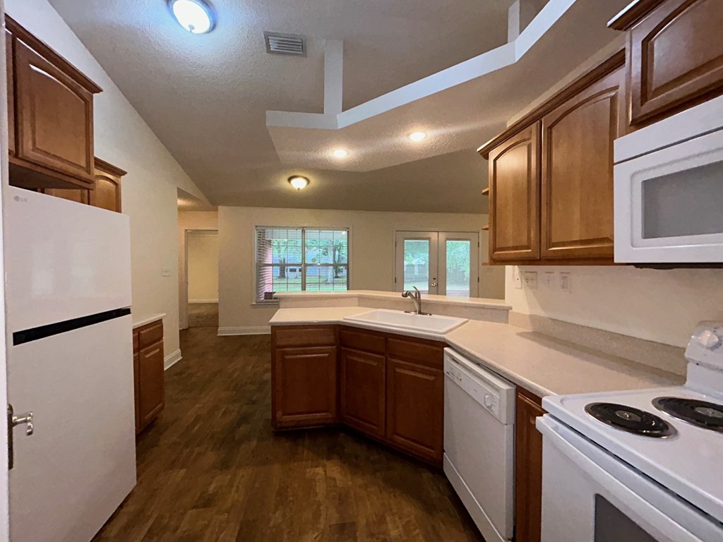 A kitchen with white appliances and wooden cabinets.