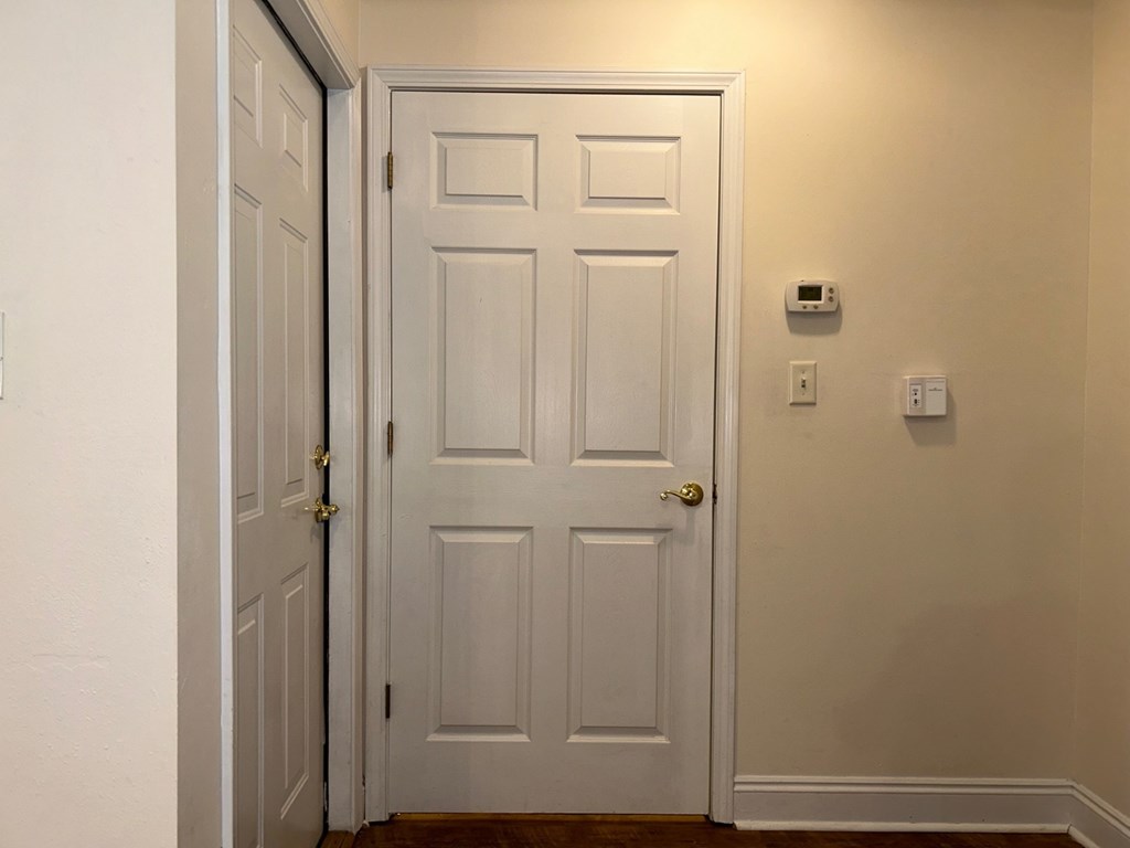 A white door with a gold handle is open to a hallway.
