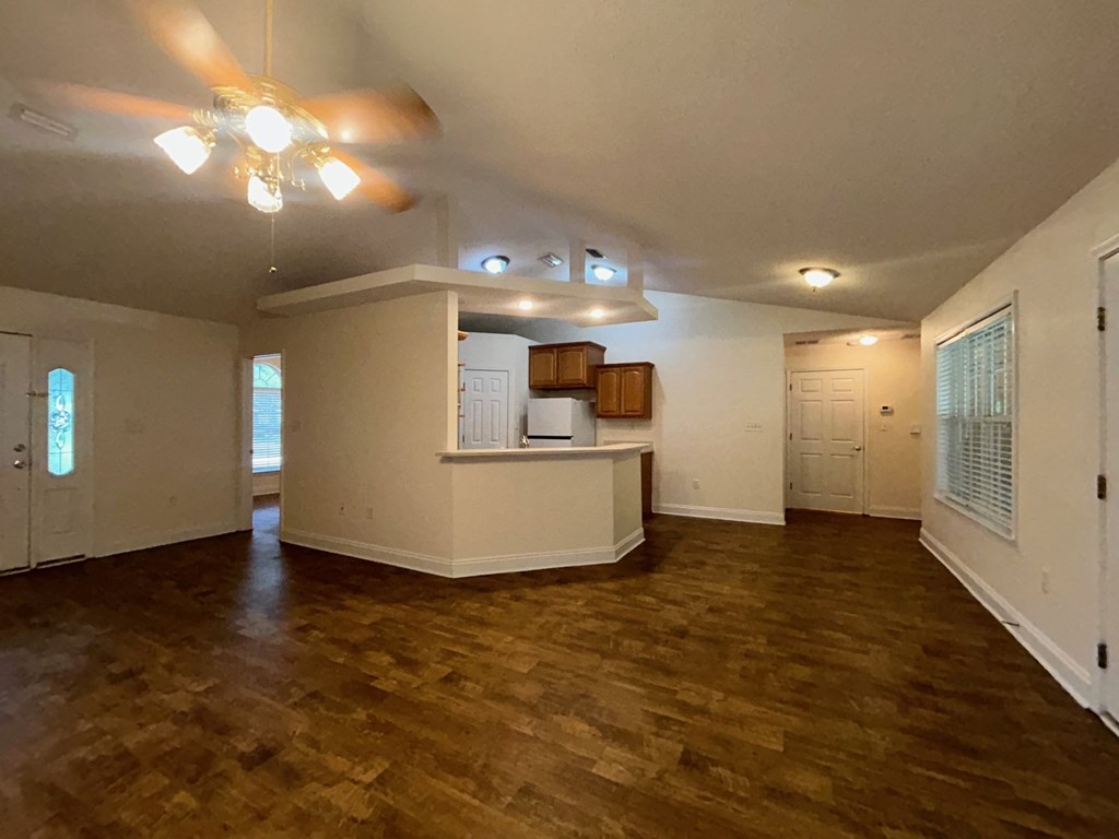 A room with a ceiling fan and wooden flooring.
