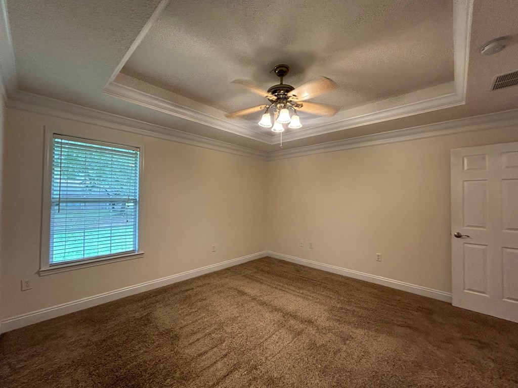 A room with a ceiling fan and carpeted floor.