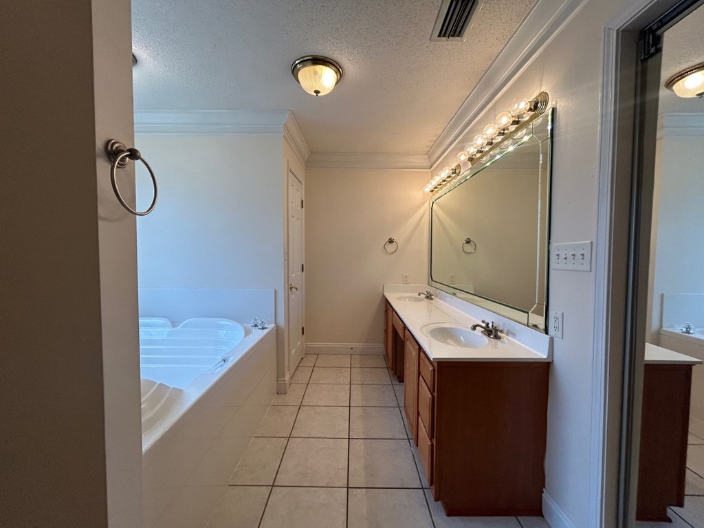 A bathroom with a white tub and brown vanity.