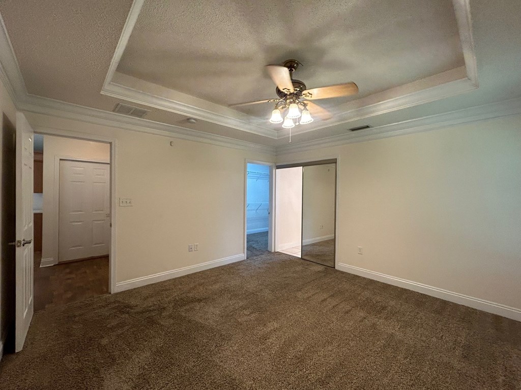 A room with a ceiling fan and carpeted floor.