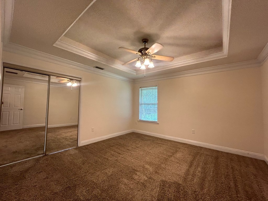 A room with a ceiling fan and a window with blinds.
