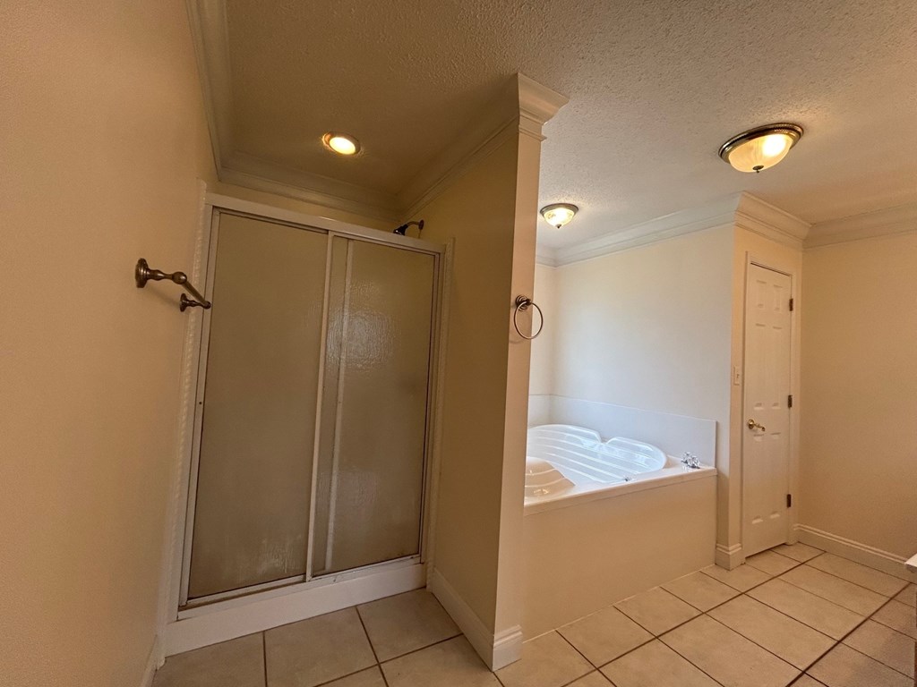 A bathroom with a glass shower door and a white door.