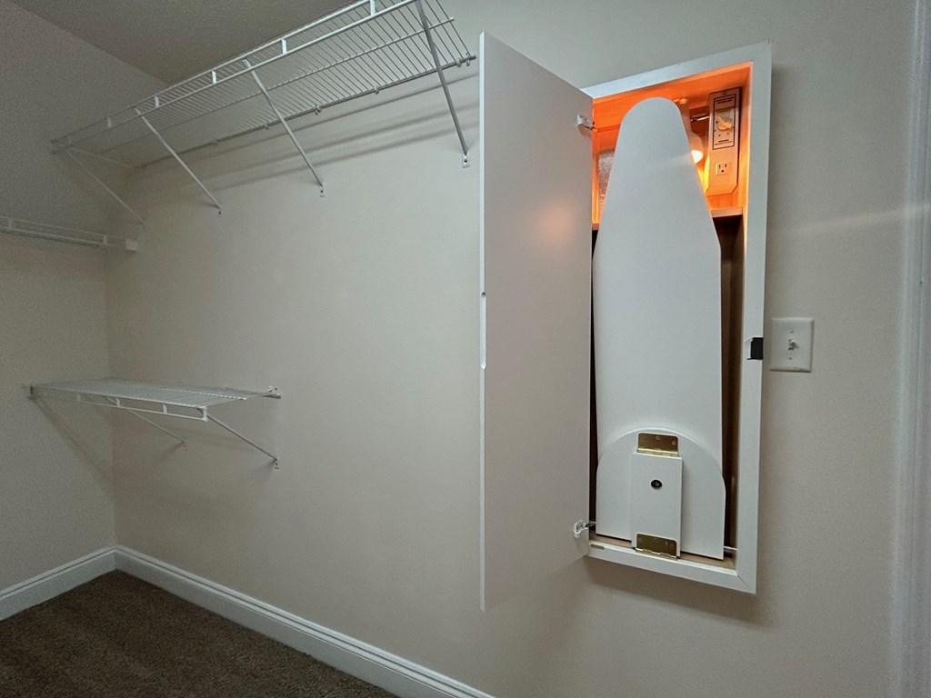A white closet with a white shelf and a white door.