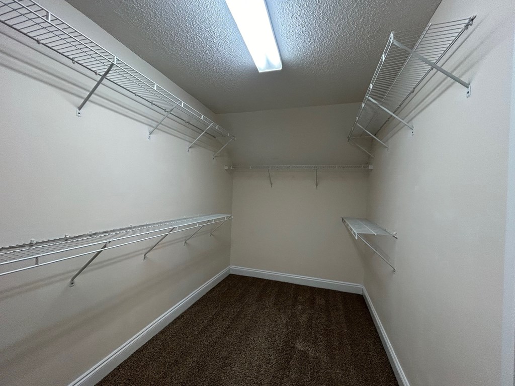 A walk-in closet with white walls and shelving.