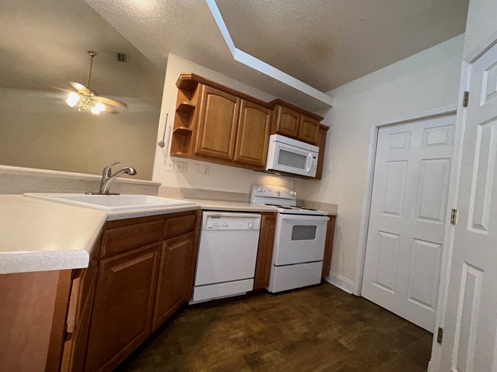 A kitchen with wooden cabinets and white appliances.