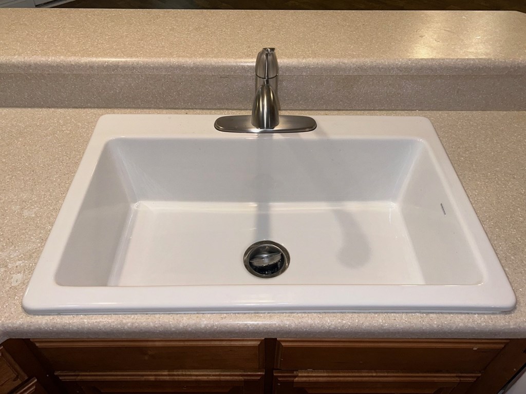A white sink with a silver faucet and a drain in the middle.