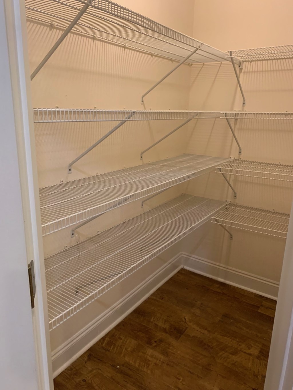 Empty white shelves in a room with wood flooring.