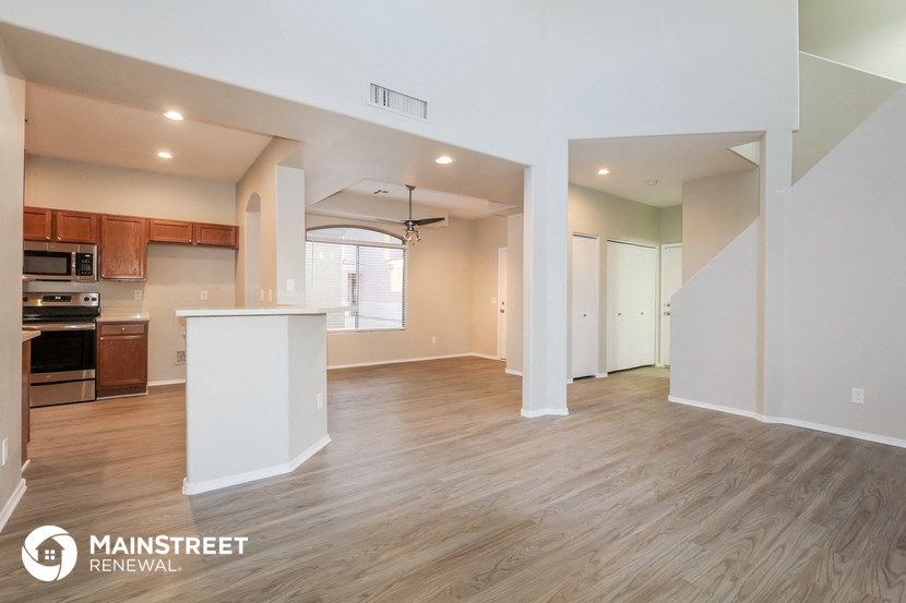 the living room and kitchen of an apartment with wood flooring