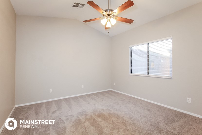 the spacious living room with carpeting and a ceiling fan
