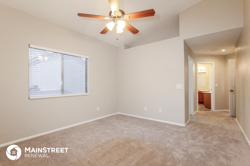the spacious living room with ceiling fan and carpeting