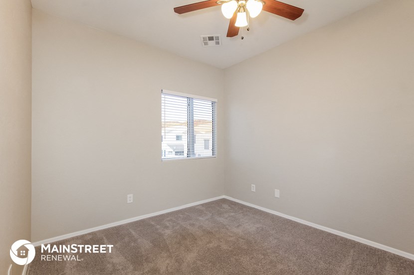 the spacious living room with carpeting and a ceiling fan