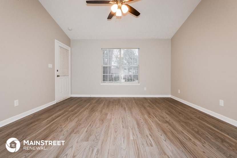 the spacious living room with hardwood floors and a ceiling fan