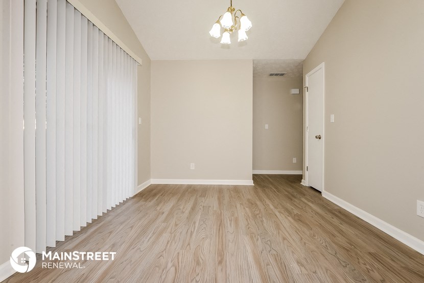 the spacious living room with wood flooring and white walls