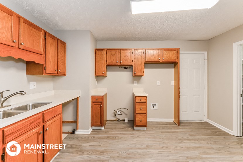 a kitchen with wooden cabinets and a sink and a doorway