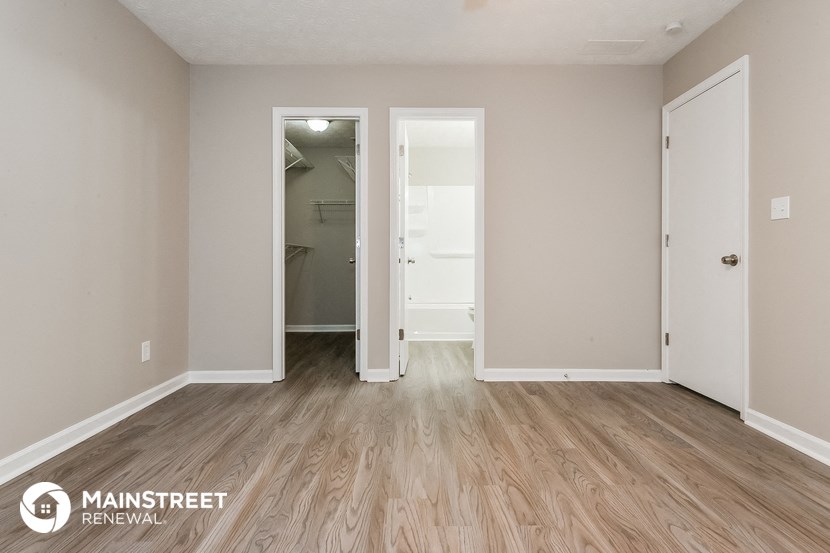 the living room of an apartment with wood flooring and a mirrored closet