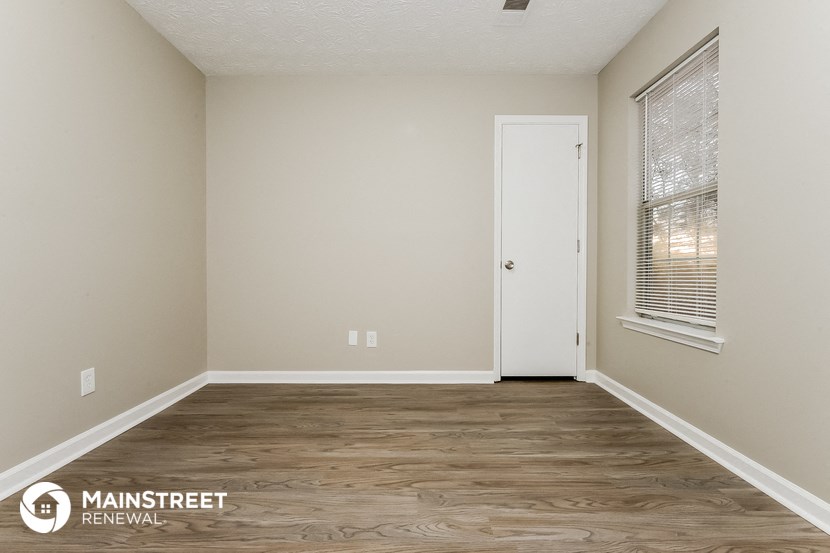 the interior of an empty room with wood flooring and a door