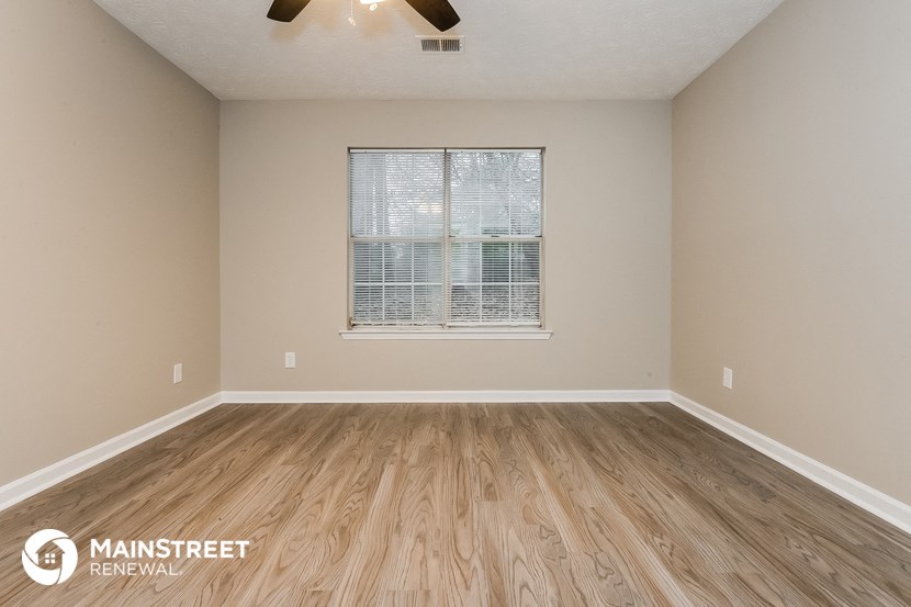 the spacious living room with wood flooring and a window