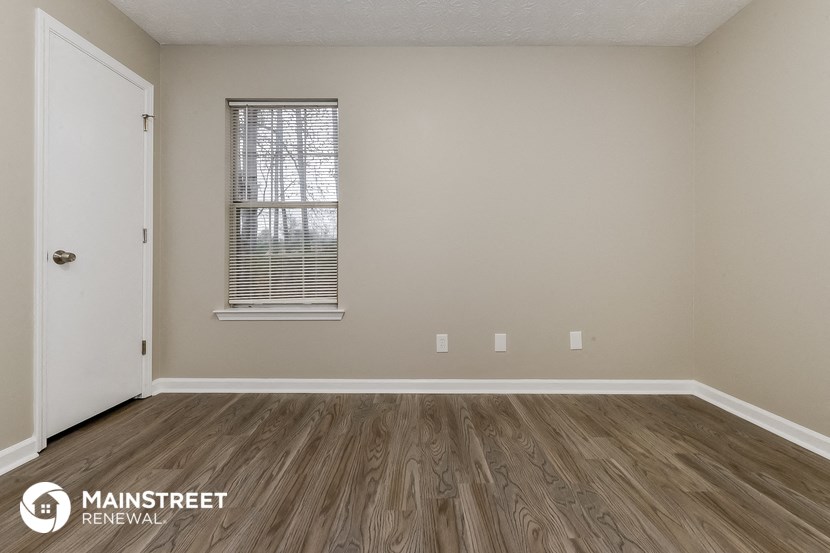 the spacious living room with wood flooring and a window