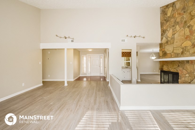 an empty living room with a fireplace and a stone wall