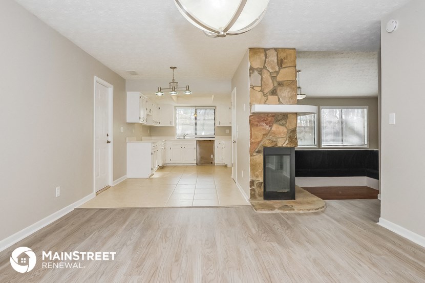 a renovated living room and kitchen with a fireplace