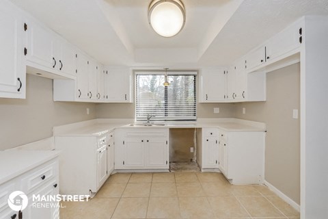 a large white kitchen with white cabinets and a window