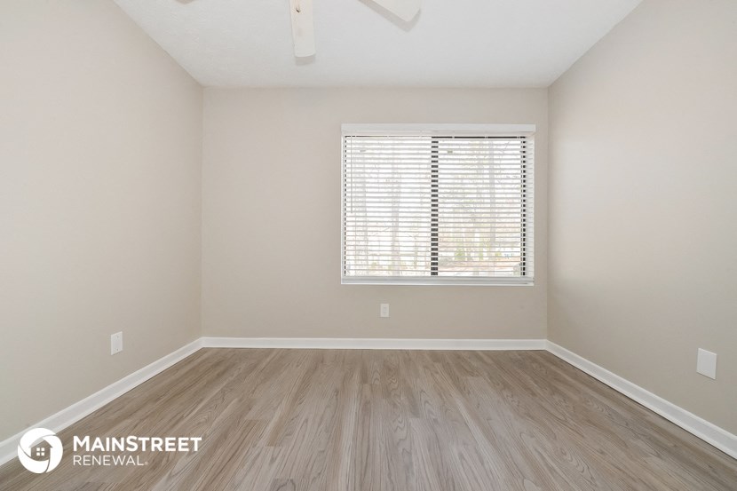 the spacious living room with wood flooring and a window