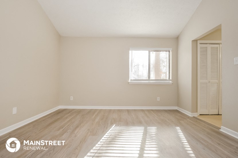 the spacious living room with a window and wood flooring