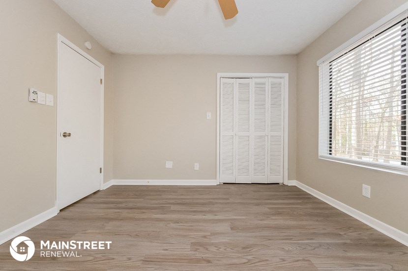 the living room of a home with wood flooring and large windows