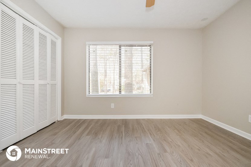 the living room of an apartment with wood flooring and a window