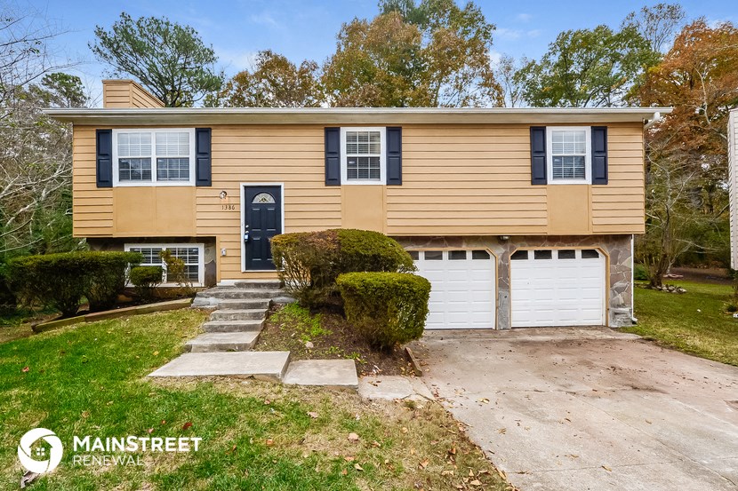 a tan and black house with two garage doors and a driveway