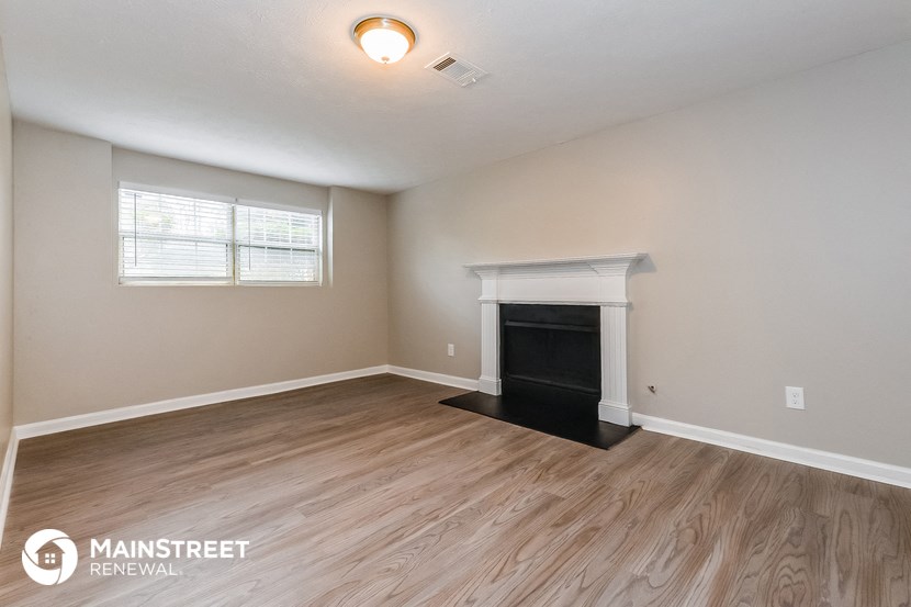 the living room of an apartment with wood flooring and a fireplace