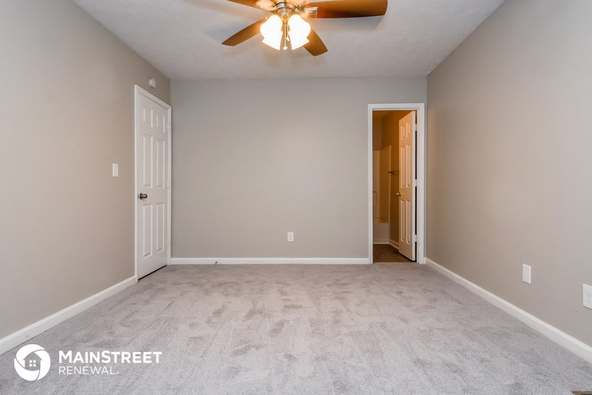 the spacious living room with carpeted floors and a ceiling fan