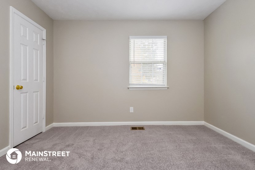 a carpeted room with a white door and a window