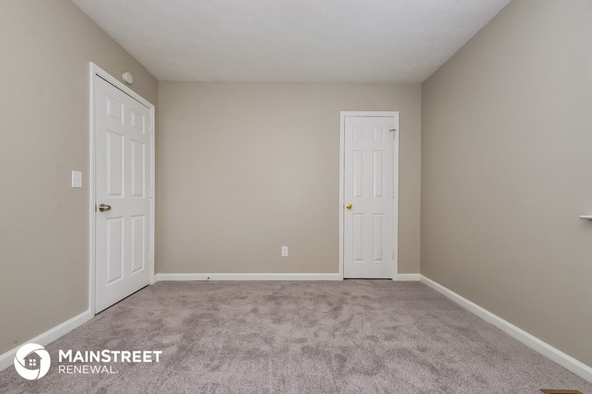 a bedroom with two doors and a carpeted floor