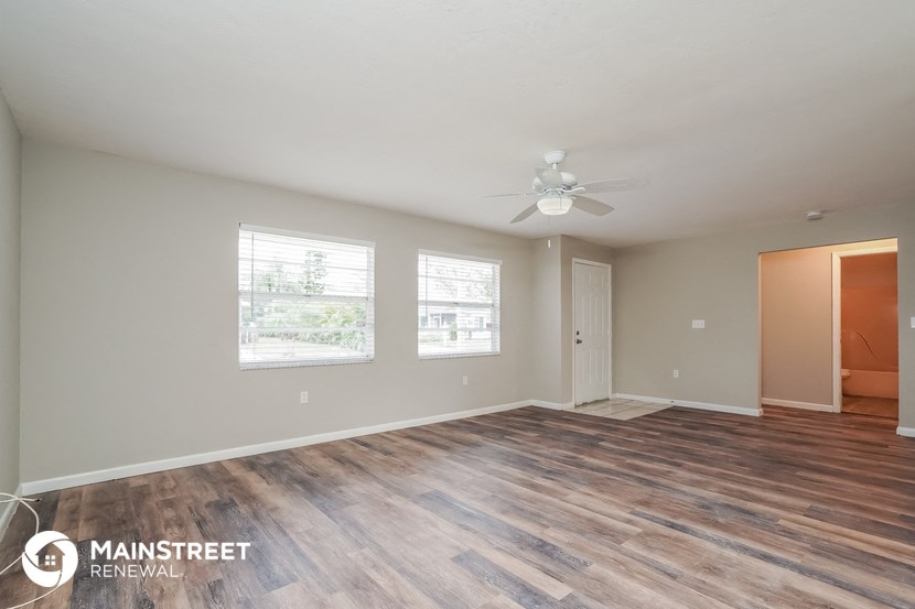 the living room and dining room with wood flooring and a ceiling fan