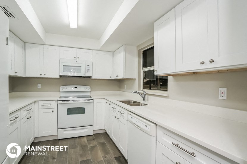 a kitchen with white cabinets and white appliances and white counter tops