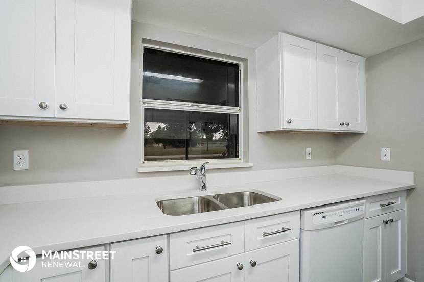 a kitchen with white cabinets and a sink and a window