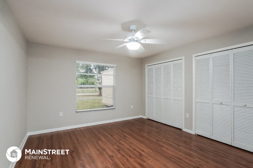 the living room is spacious and has a large window and wood flooring