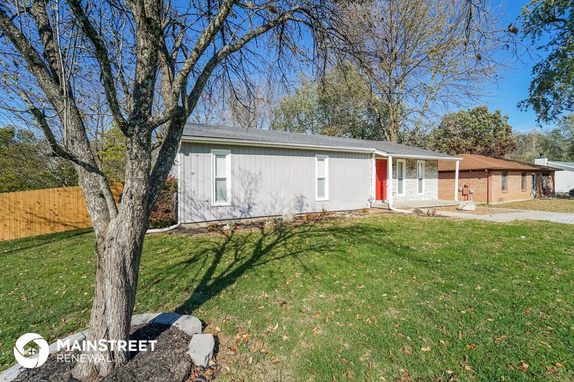 a small white house with a yard and a tree