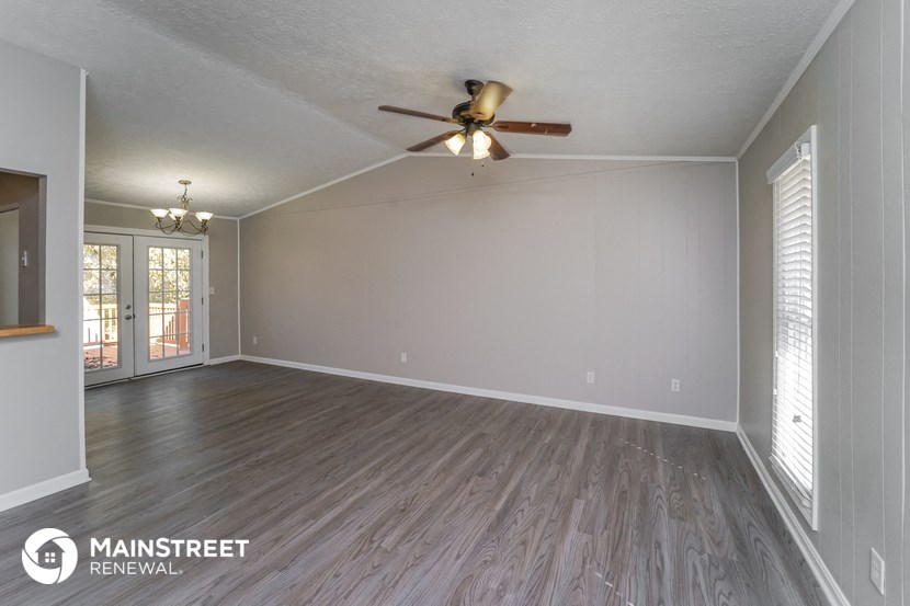 the living room of an empty house with a ceiling fan