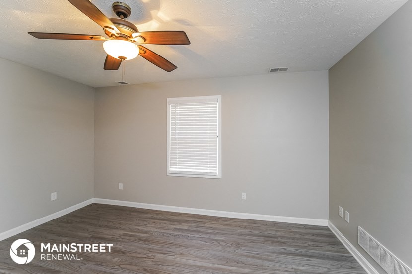 the spacious living room with ceiling fan and wood flooring