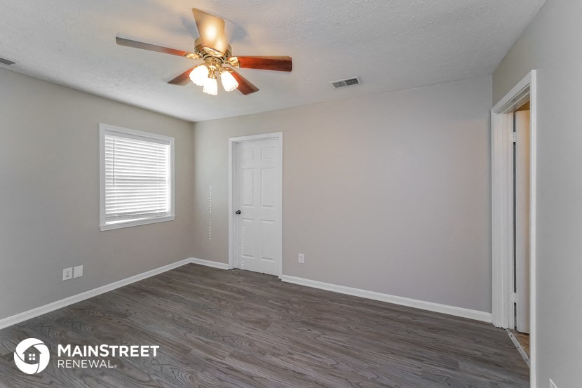 the spacious living room with ceiling fan and wood flooring