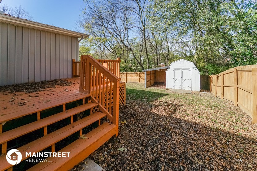 a backyard with a deck and a fence and a shed